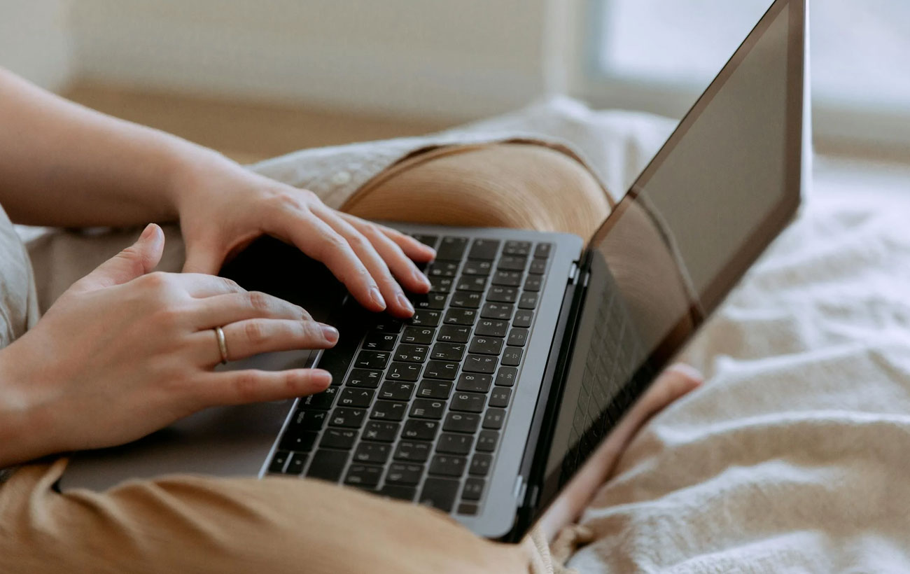 Lady In Bed Browsing Her Laptop