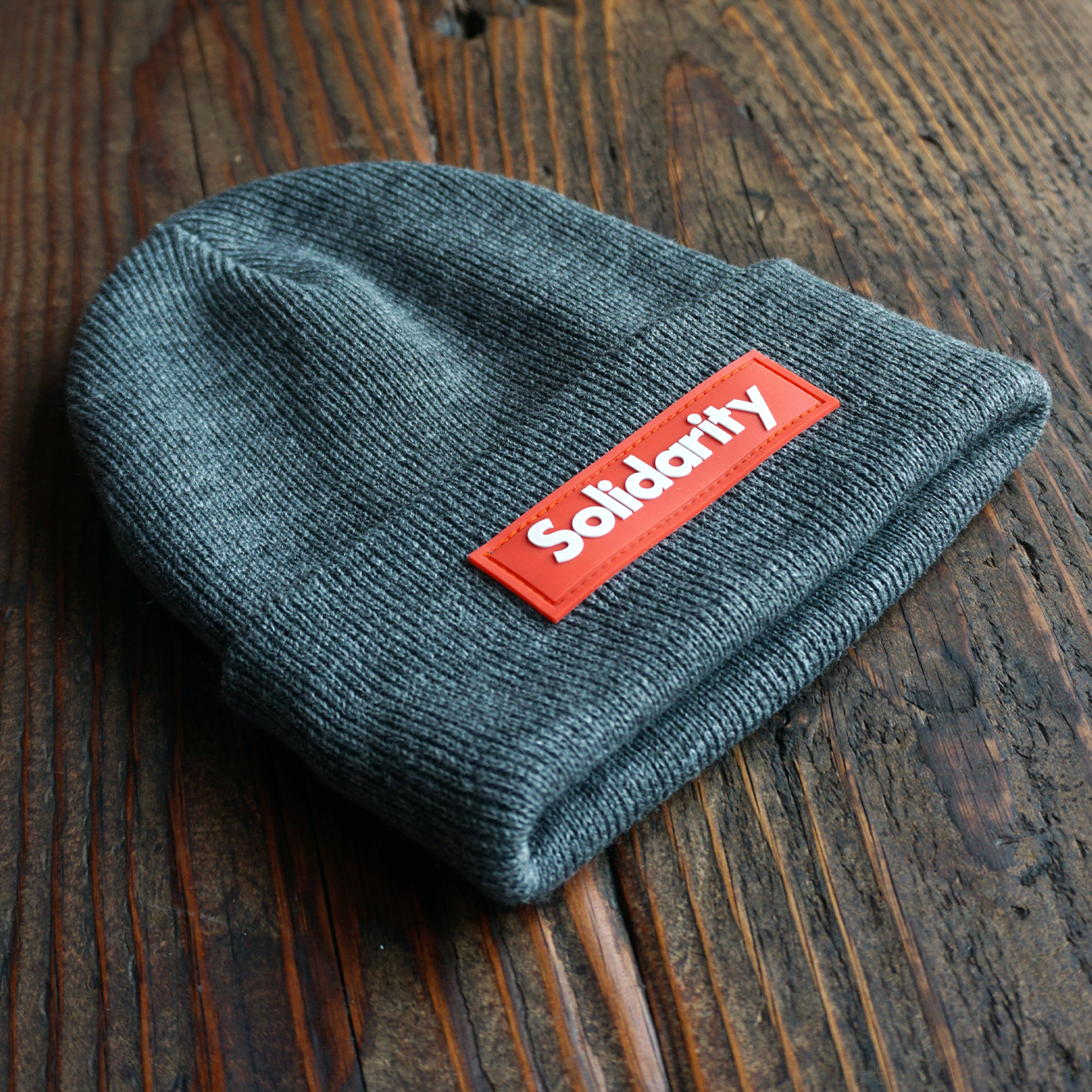 One MVMT Solidarity Beanie on Wooden Table