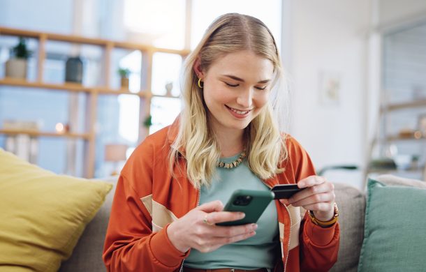 Blonde girl on the phone checking out her cart on her iPhone using her credit card