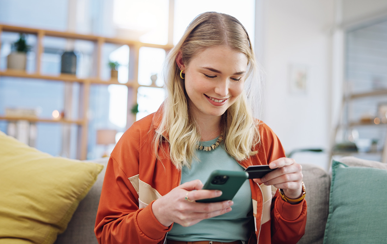 Blonde girl on the phone checking out her cart on her iPhone using her credit card